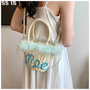 Detail of woven straw bucket bag with blue faux fur trim and pearl strap decoration