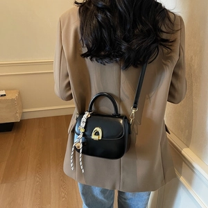 Chic black leather crossbody bag with gold buckle and polka dot scarf detail
