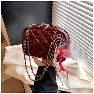 Detail of burgundy quilted crossbody bag with gold chain strap and floral charms