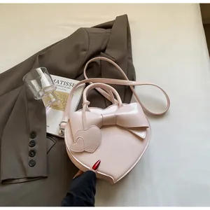 Detail of pink heart-shaped handbag with a large bow and elegant leather charms