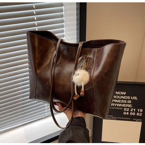 Detailed view of deep brown vintage tote bag with glossy leather and plush charm