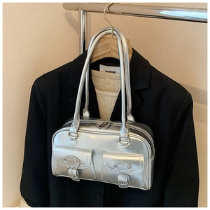 Detail view of metallic silver tote bag with buckle pockets on a black blazer background