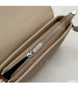 Detail view of the beige saddle bag showing inner leather texture and smooth metal zipper