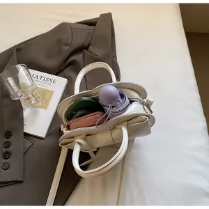 Interior view of off-white bow bag showing capacity for umbrella, wallet, and phone