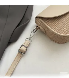 Detail of detachable metal hook and adjustable shoulder strap on khaki crossbody bag