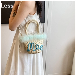 Detail of woven straw bucket bag with blue faux fur trim and pearl bead shoulder strap