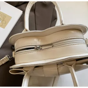 Detail view of heart-shaped cream bag with metal zipper and smooth leather texture