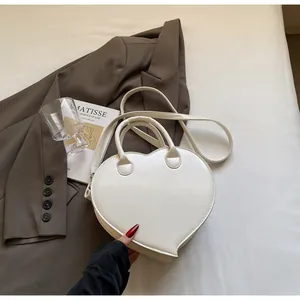 Detailed close-up of white heart-shaped crossbody bag with glossy leather finish
