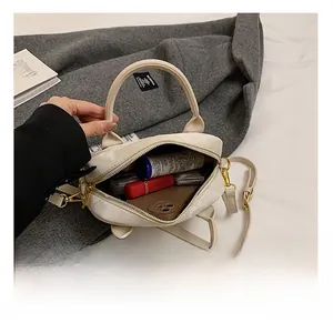 Vue intérieure du sac polochon en cuir crème montrant l'espace pour téléphone et maquillage