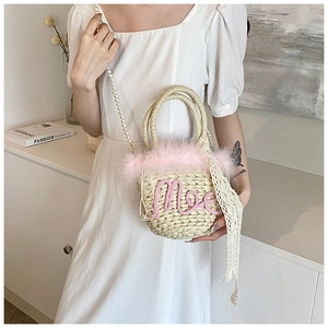 Detail of beige woven bucket bag featuring pink plush trim and beaded pearl shoulder strap