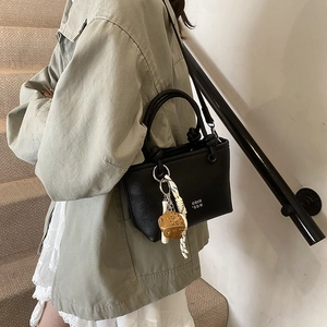Retro black lychee textured bucket bag with decorative pendant and crossbody strap