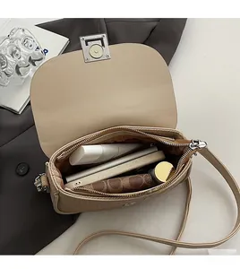 Interior storage view of beige saddle bag showing phone, lipstick and accessories