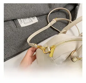 Détails de la quincaillerie dorée et du zip sur le sac oreiller en cuir blanc cassé