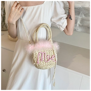 Close-up of woven straw bucket bag with pink feathers and pearl strap detail