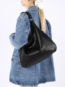 Détail du sac hobo en cuir grainé noir avec large bandoulière porté par un mannequin