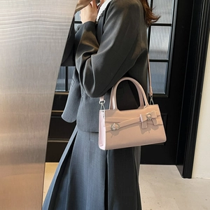 Pink faux leather crossbody bag with decorative silver eyelets and side bow details