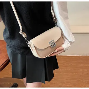 Detail of beige saddle bag showing woven texture, smooth leather and silver metal clasp
