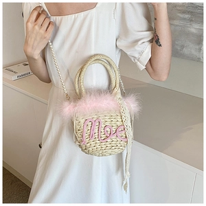 Detail of woven straw bag featuring pink feather trim and pearl crossbody strap