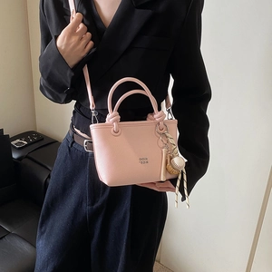Chic light pink bucket bag for women with baseball themed charms and crossbody strap