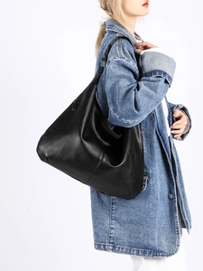 Vue latérale d'un grand sac hobo noir à texture litchi porté par un mannequin