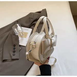 Detailed close-up of a white heart-shaped lacquer bag with a large bow and metallic zip