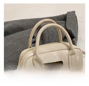 Détail du sac beige montrant la texture marbrée et le logo triangle doré