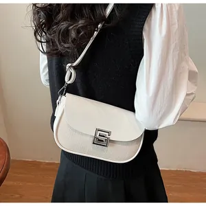 Detail of a beige leather and woven saddle bag with a silver S-shaped metal lock