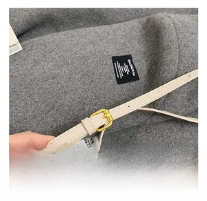 Détail de la bandoulière réglable en cuir beige avec boucle dorée et œillets élégants