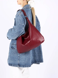Détail d'un sac hobo bordeaux avec texture en cuir souple et boucle métallique