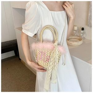 Detail of straw bucket bag with pink feathers, pearl chain, and lace bow decoration