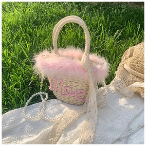 Close-up of woven straw bag with pink feather trim, pearl strap and lace details
