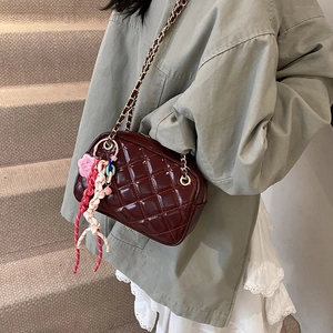 Dark red quilted crossbody bag with golden chain strap and creative charm detail