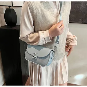 Detail of light blue crossbody bag with silver S-shaped buckle and textured fabric
