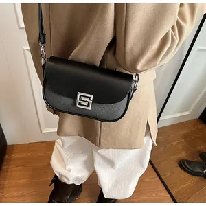Detail of black crossbody bag with textured fabric, leather flap, and silver S-shaped buckle