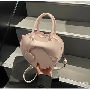 Detail of pink heart-shaped crossbody bag with a large bow and a heart charm