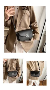 Detail of black faux leather crossbody bag with lychee texture and silver metal buckle