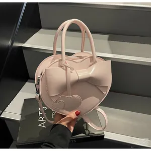 Detailed view of pink heart-shaped handbag with a large leather bow and heart charms