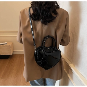 Détail du sac à main noir en forme de cœur avec nœud et finition brillante sur le dos