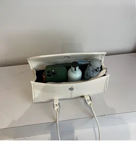 Interior view of cream white shoulder bag showing spacious storage for phone and umbrella