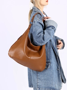 Gros plan du sac hobo en cuir grainé marron avec large bandoulière sur un modèle