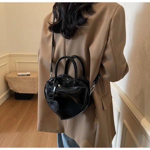 Détail du sac à main noir en forme de cœur avec un grand nœud sur le mannequin