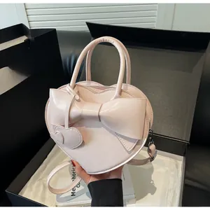 Pink heart-shaped shoulder bag with a giant bow detail and silver metal hooks