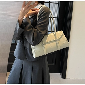 Detail of retro cream underarm bag with decorative leather straps and silver buckles