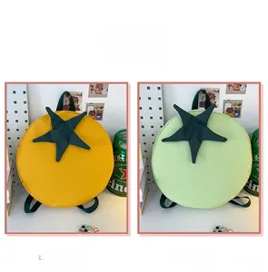 Detail view of round tomato-shaped backpacks in yellow and light green color options