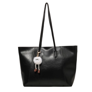 Classic large black tote bag in textured faux leather featuring a cute white plush charm