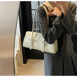 Detail of off-white baguette bag with vertical stitching and silver buckles on model