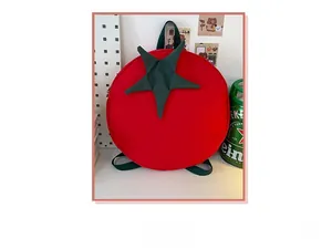Detailed close-up of a cute tomato-shaped backpack with green leaves on a white desk