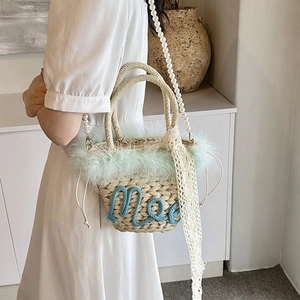 Fashionable straw bucket bag with feather trim and pearl strap for beach vacations