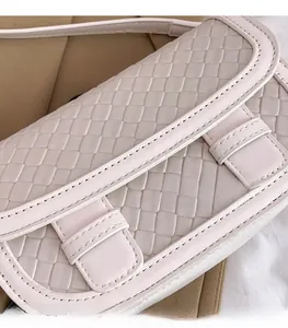 Close-up of a pink woven saddle bag showing textured faux leather and buckle details