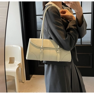 Chic beige leather underarm bag with double metal buckles shown on a model